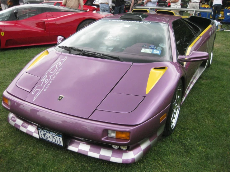 purple sports car parked on grassy field with other cars