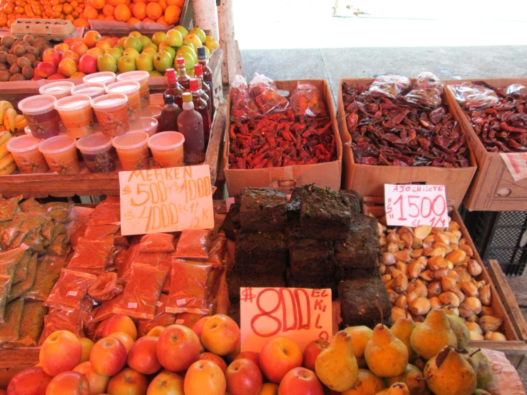 the fruit stand has apples, plums, carrots and other fruits