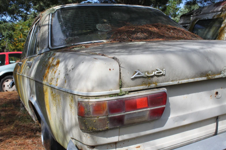 an old, dirty car sits in a yard