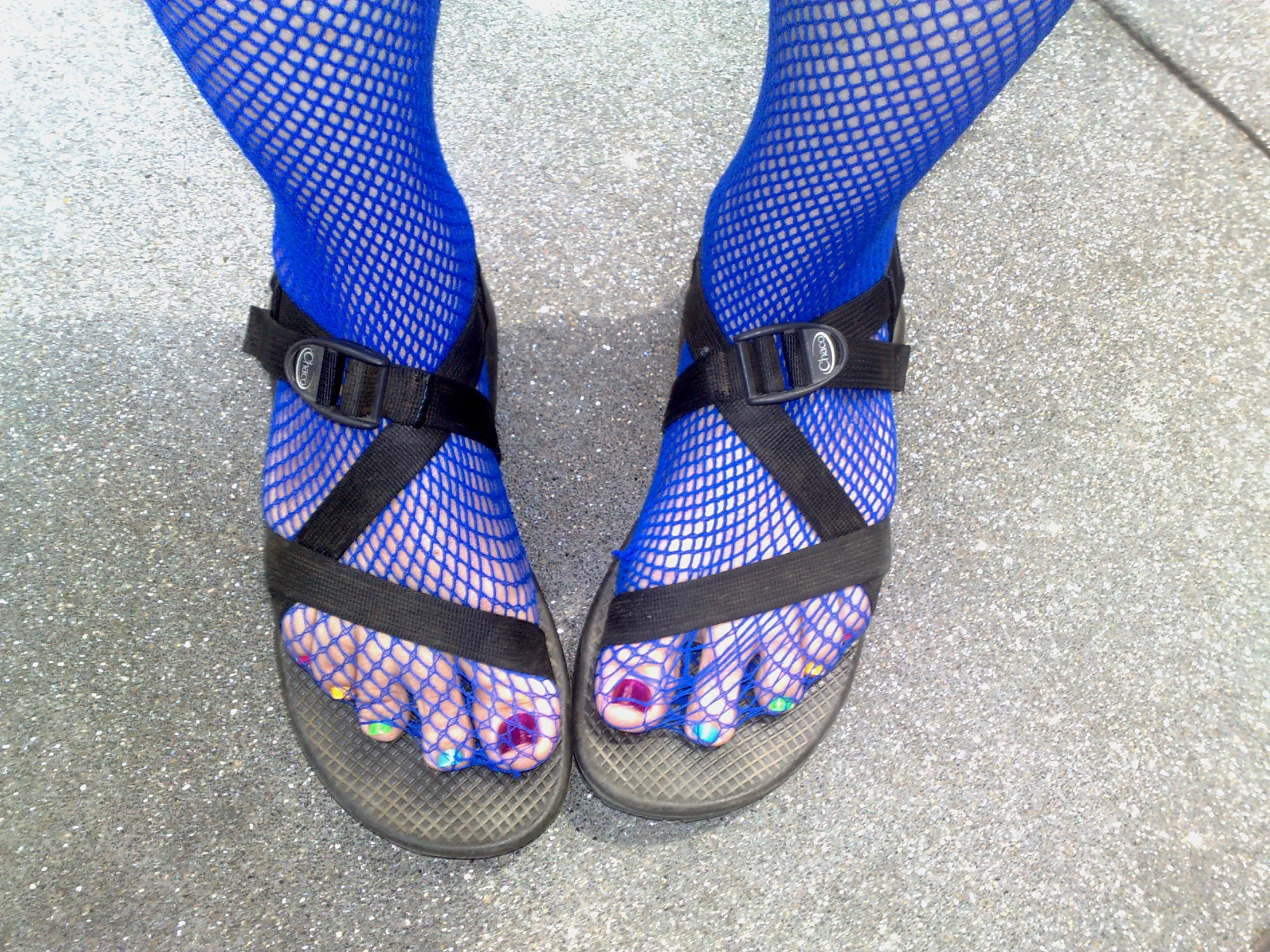 a person with blue socks and colorful shoe laces wearing sandals