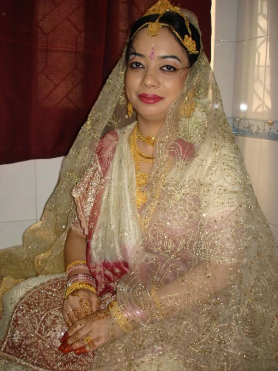 a woman with a tiara, holding soing, wearing gold jewelry and a veil