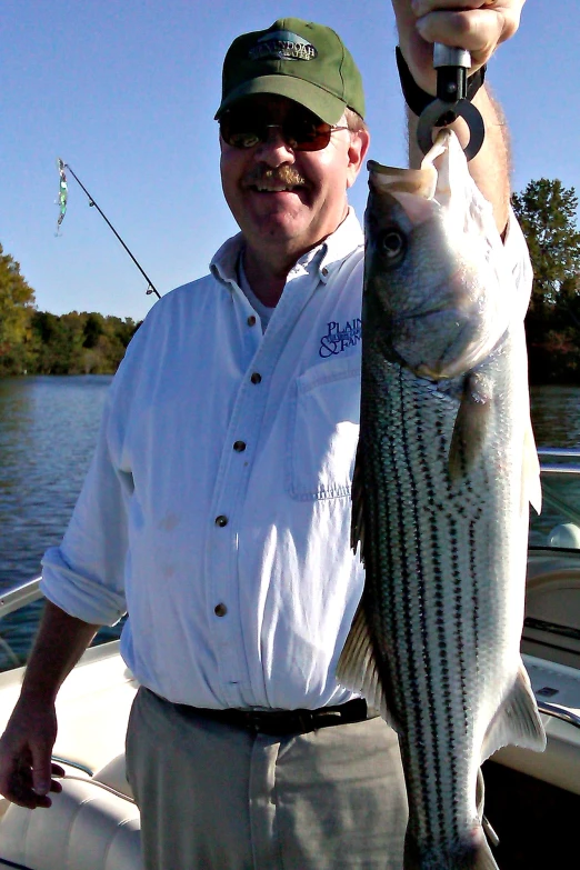 a man holding up a fish on a boat