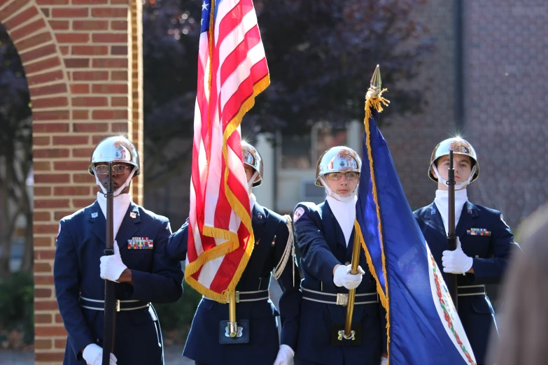 several uniformed personnel holding flags walking in a parade