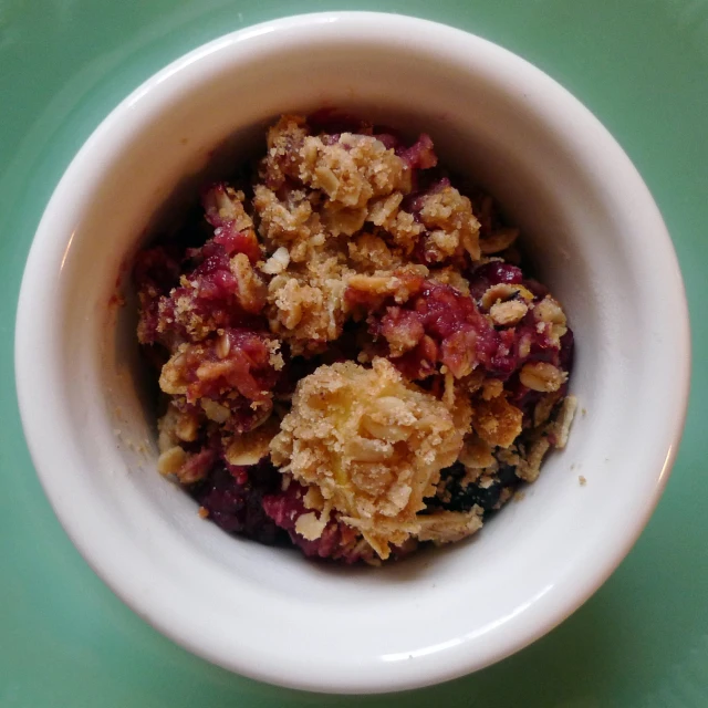 a white bowl filled with cooked food on top of a green surface