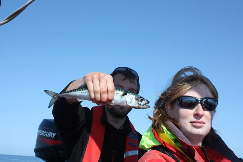 two people on a boat holding up fish