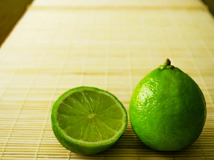 two limes and one lemon are laying on a mat