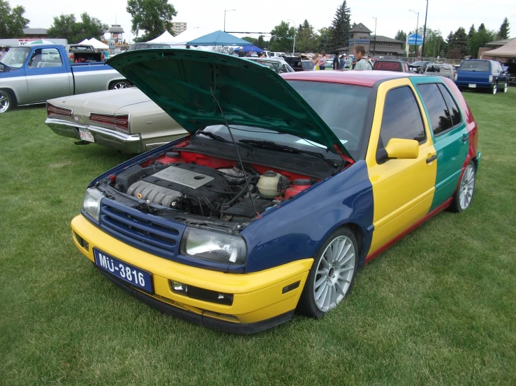 some cars on grass and one is a yellow and blue truck