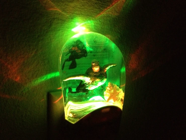 an unusual glass clock is illuminated by green lights