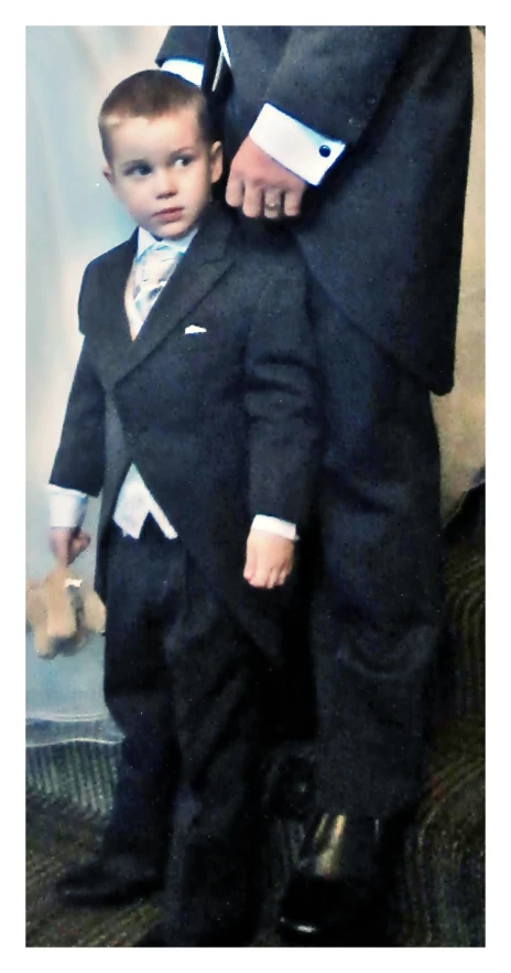 a man in a tuxedo holds his son's lap