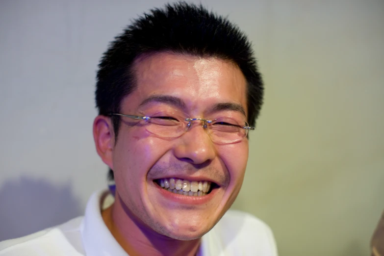 a man in glasses is smiling with the reflection of his teeth