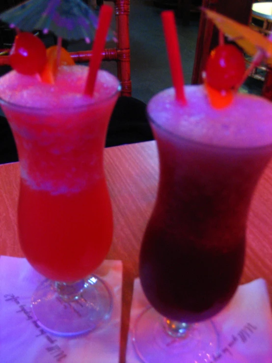 two drinks with straws sitting on a table next to each other