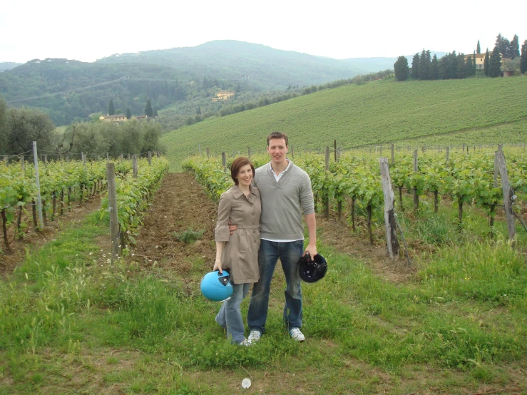 the couple pose for their picture in the middle of the vineyard