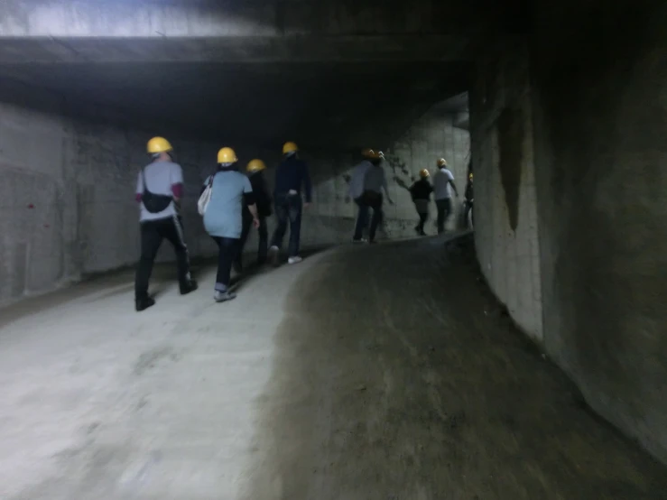 people in yellow helmets walking inside a tunnel