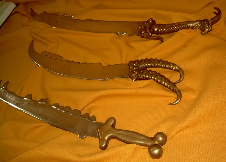 an assortment of knives displayed on a yellow cloth