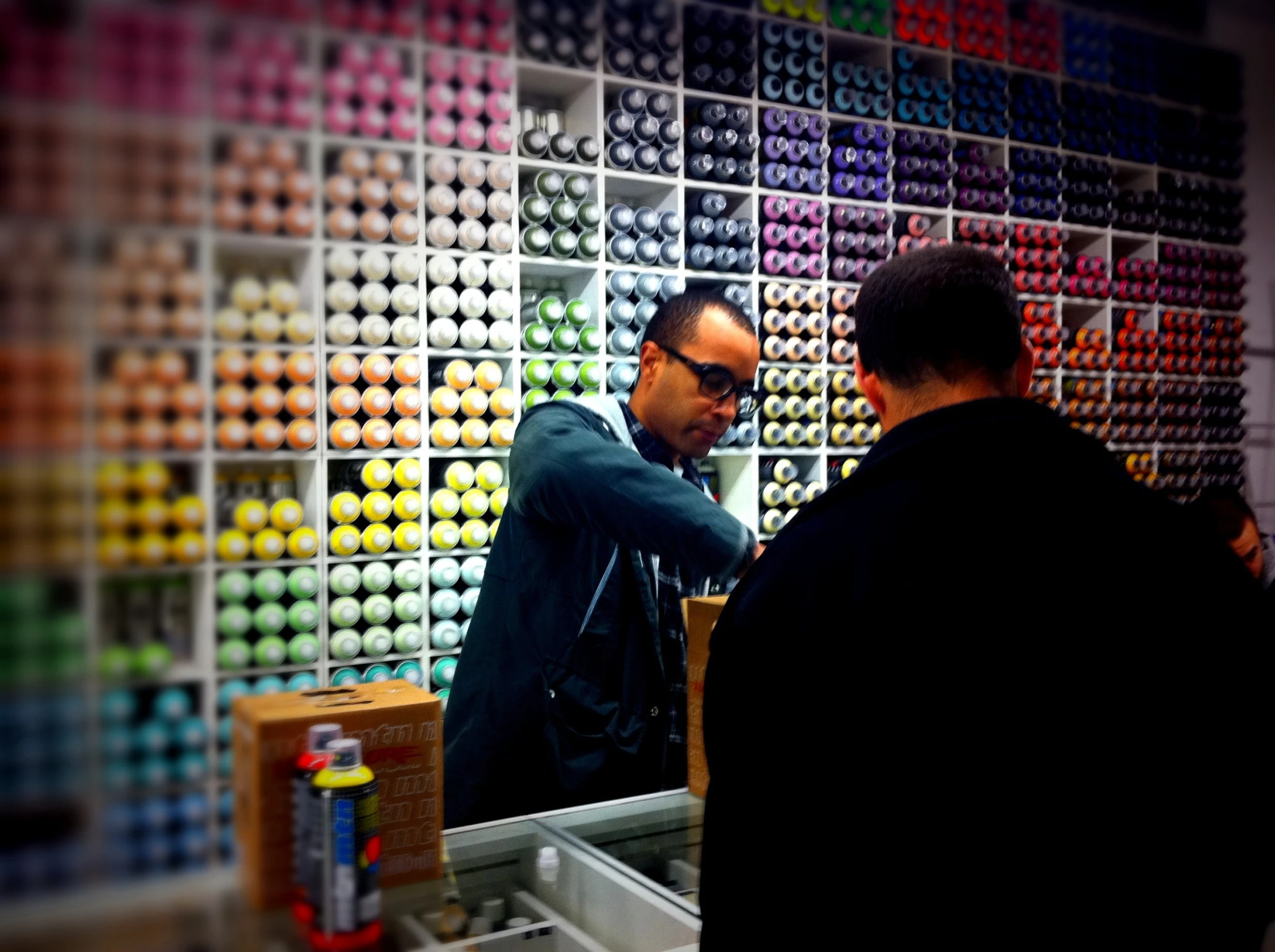 two men in a retail shop looking at the walls covered with cans