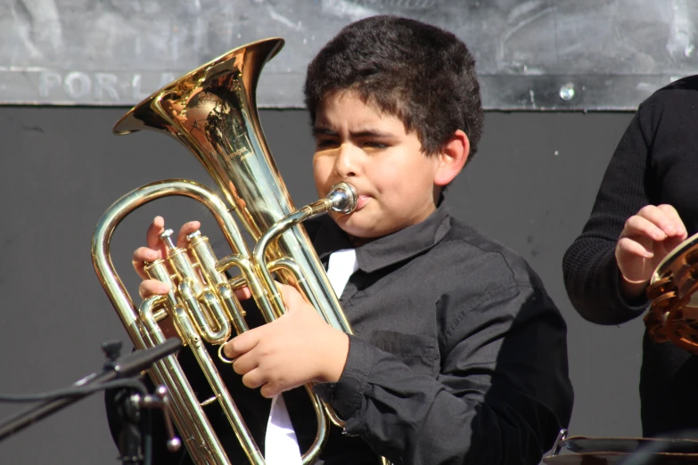 a  is playing an instrument and someone is holding his hand up to the trombone