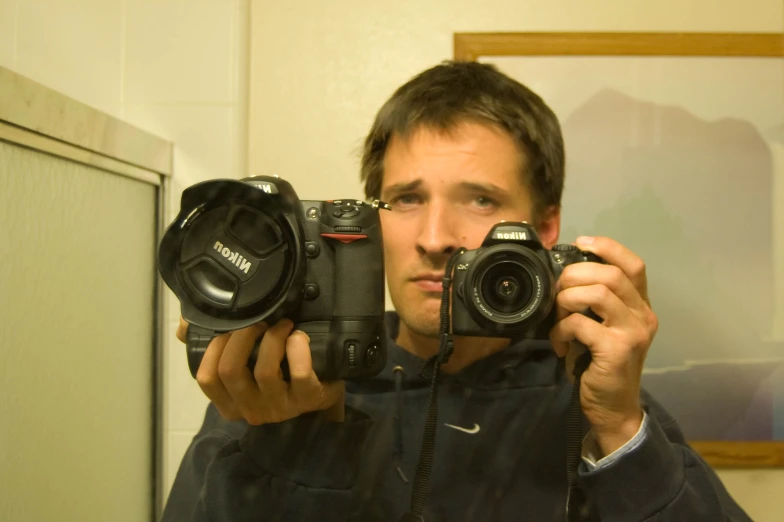 a man holding two cameras with both hands in front of his face