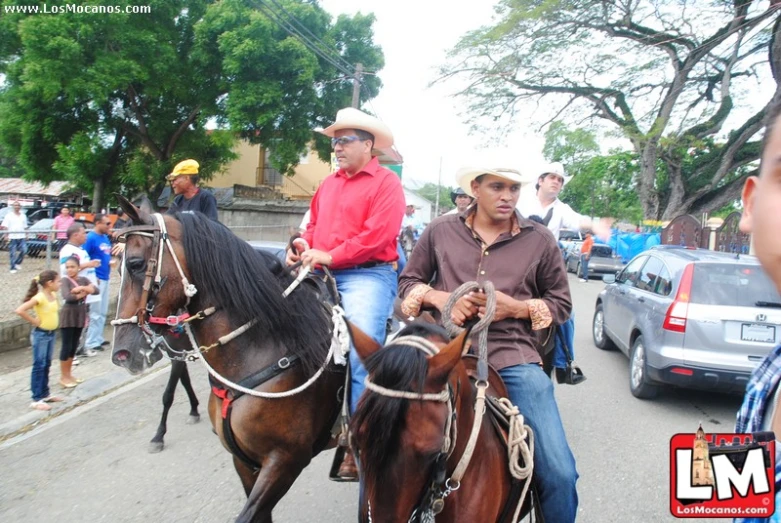 men ride horses down the street while wearing hats