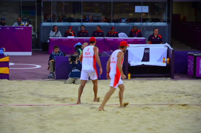 two men in red and white swimsuits playing on beach