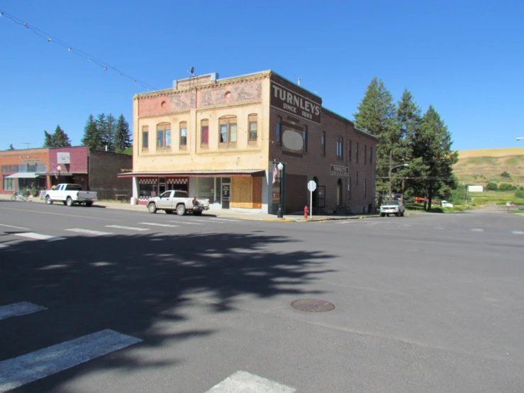 an empty town street with cars parked on the side of the road