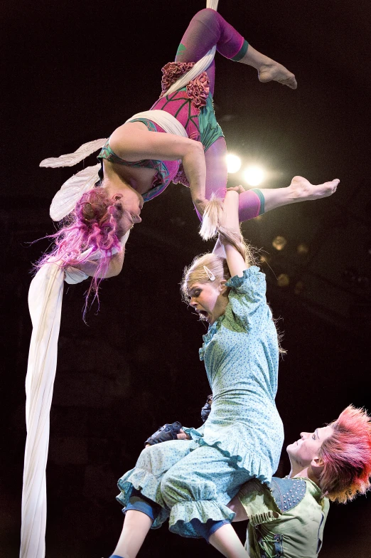 three acrobatic dancers performing an aerial trick at the circus