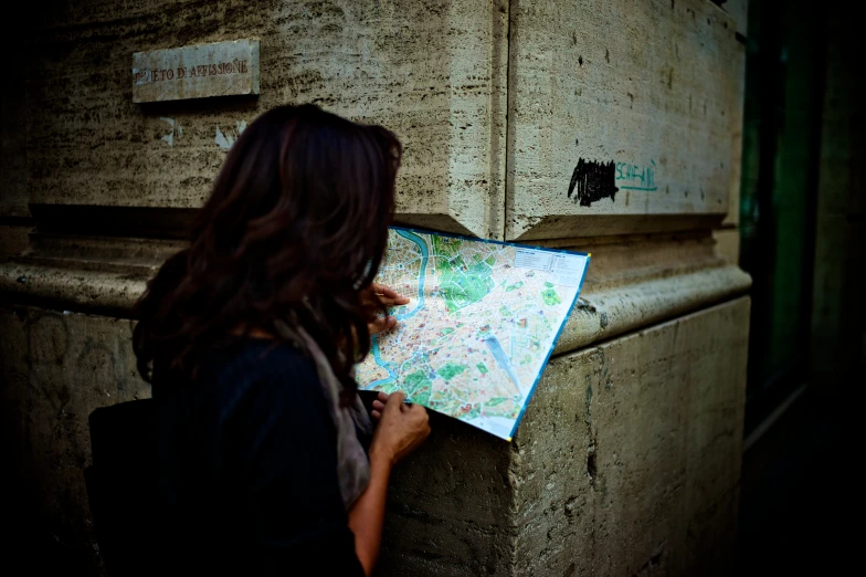 girl in dark shirt looking at the map and holding up it