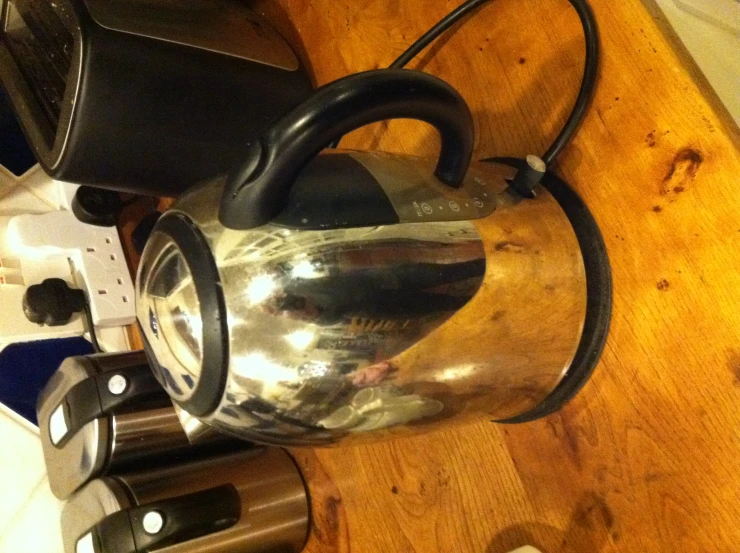 a metallic kettle sitting on top of a wooden counter