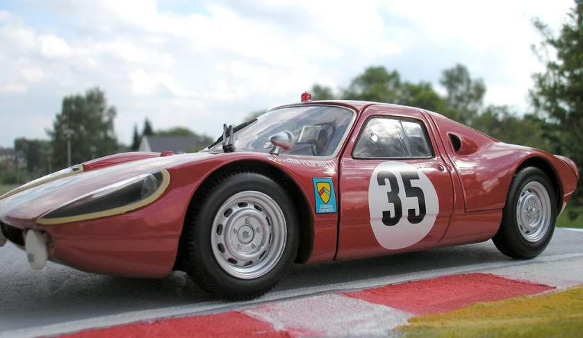 a very small red sports car with numbers on the side