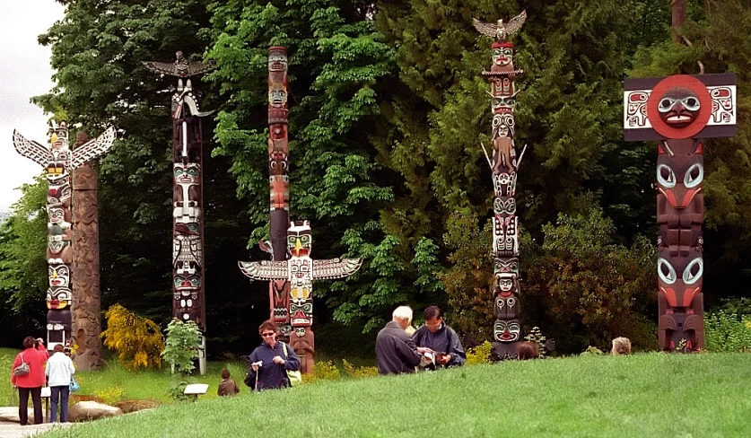 some people standing in front of totem poles