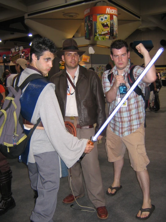 three men at an airport holding onto two giant light swords