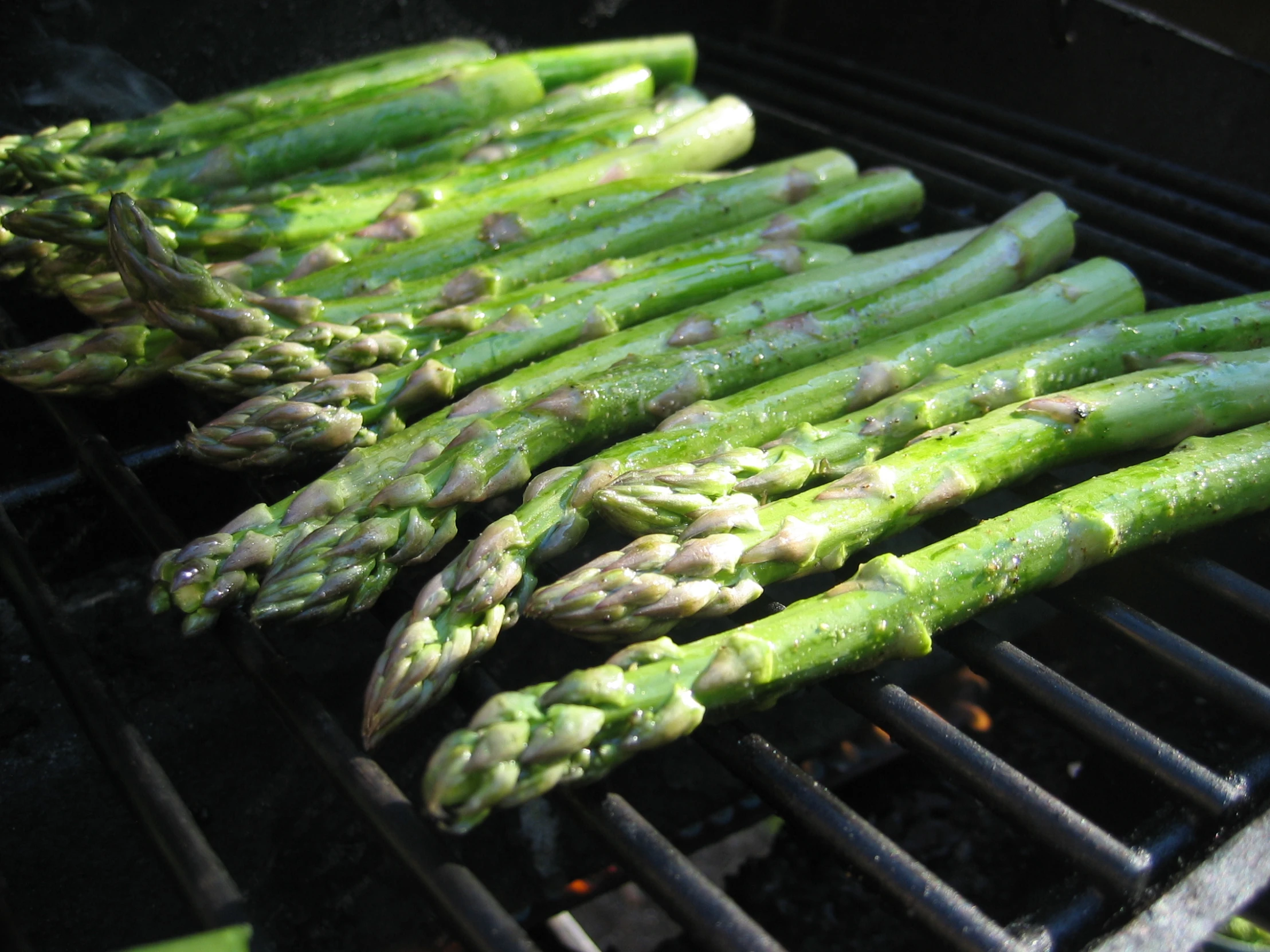 several asparagus on a charcoal grill in the sun