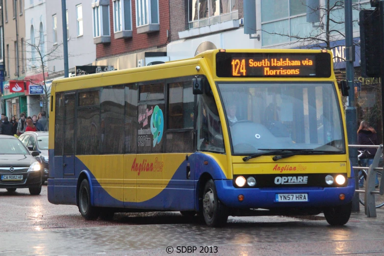 a yellow and blue bus on a street next to some buildings