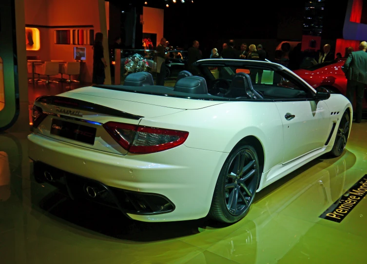 an automobile showroom with people standing around and looking at it