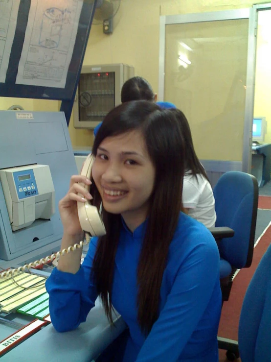 a woman sitting in front of a phone in an office