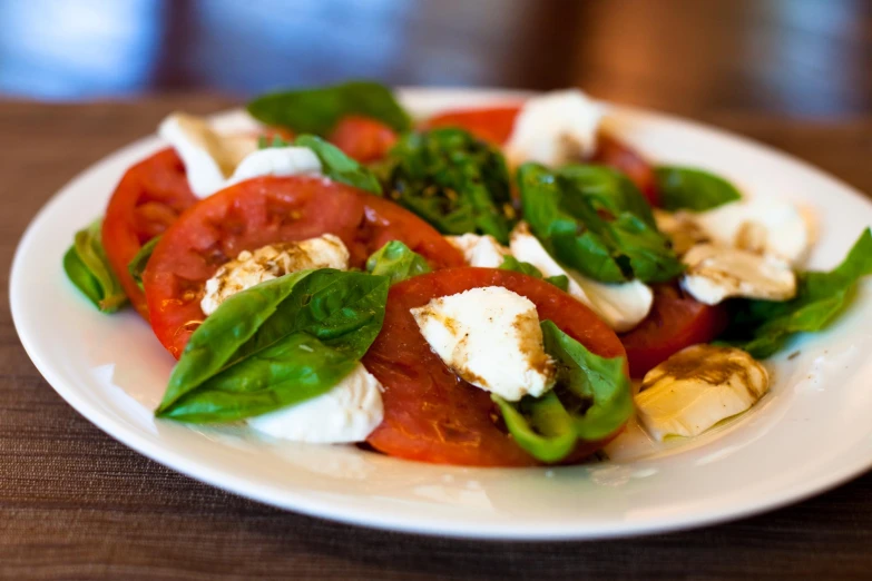 a salad with green and tomato leaves, mozzarella and basil