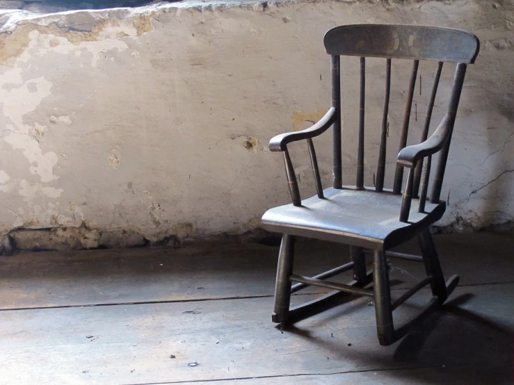 a small wooden rocking chair next to a building