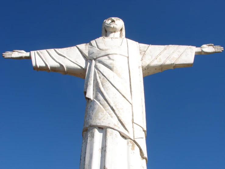 a large statue of christ standing in front of a clear blue sky