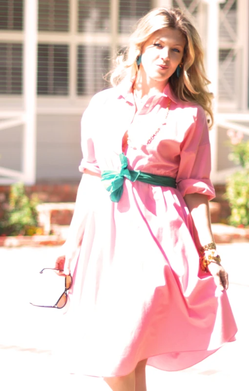 a women with blond hair and sunglasses in pink dress