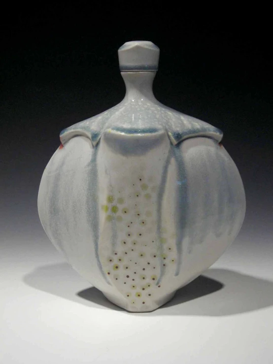 a white ceramic urn with some gold dots on it