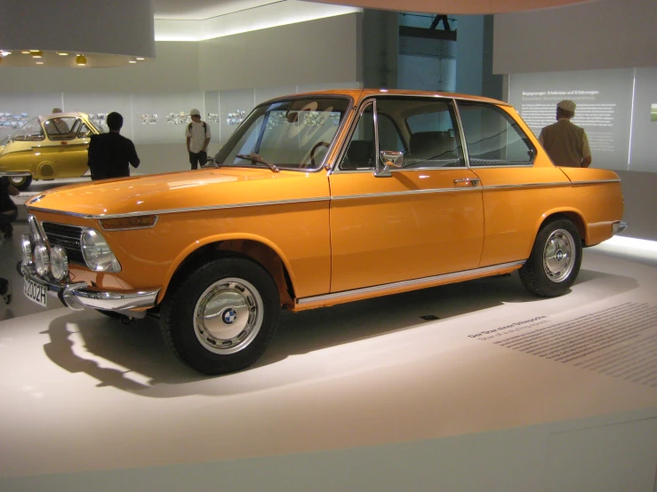 there is an orange car on display at the museum