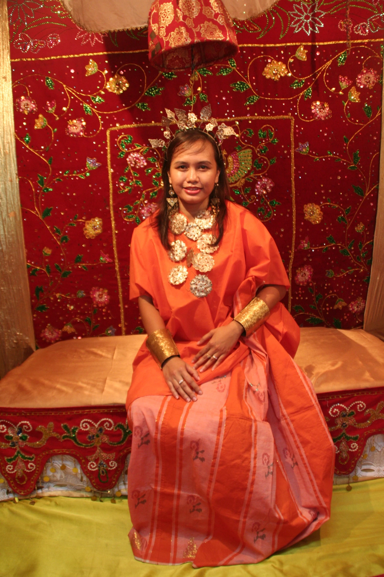 a woman sitting on a bed with jewelry on her head