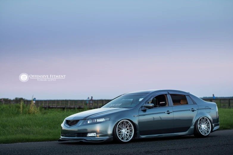 the silver car is on a paved road by some grass