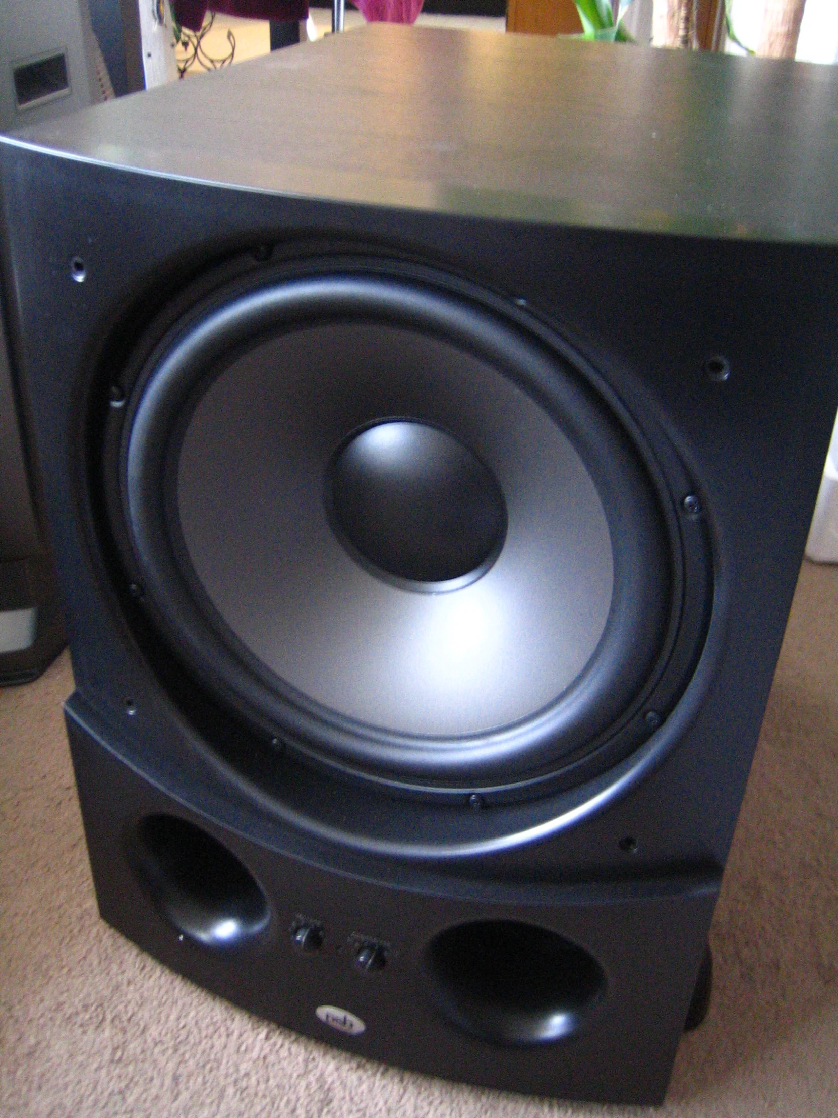 a large speaker sits on a carpeted floor