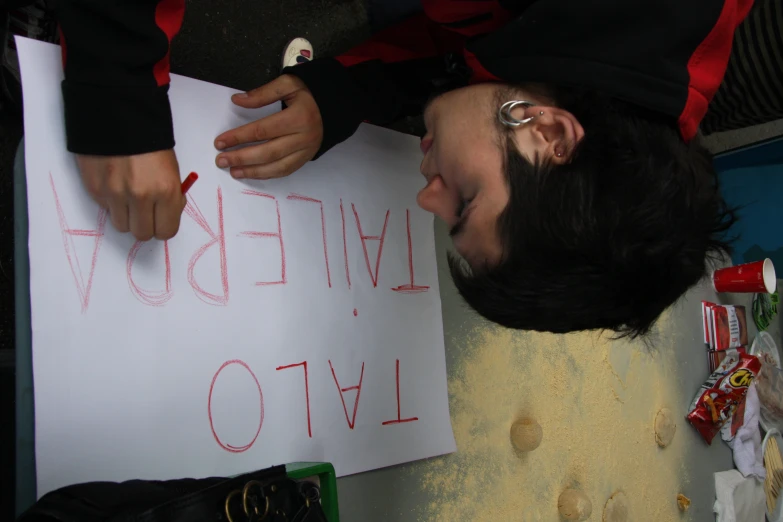 a boy with a drawing in hand writing letters on paper