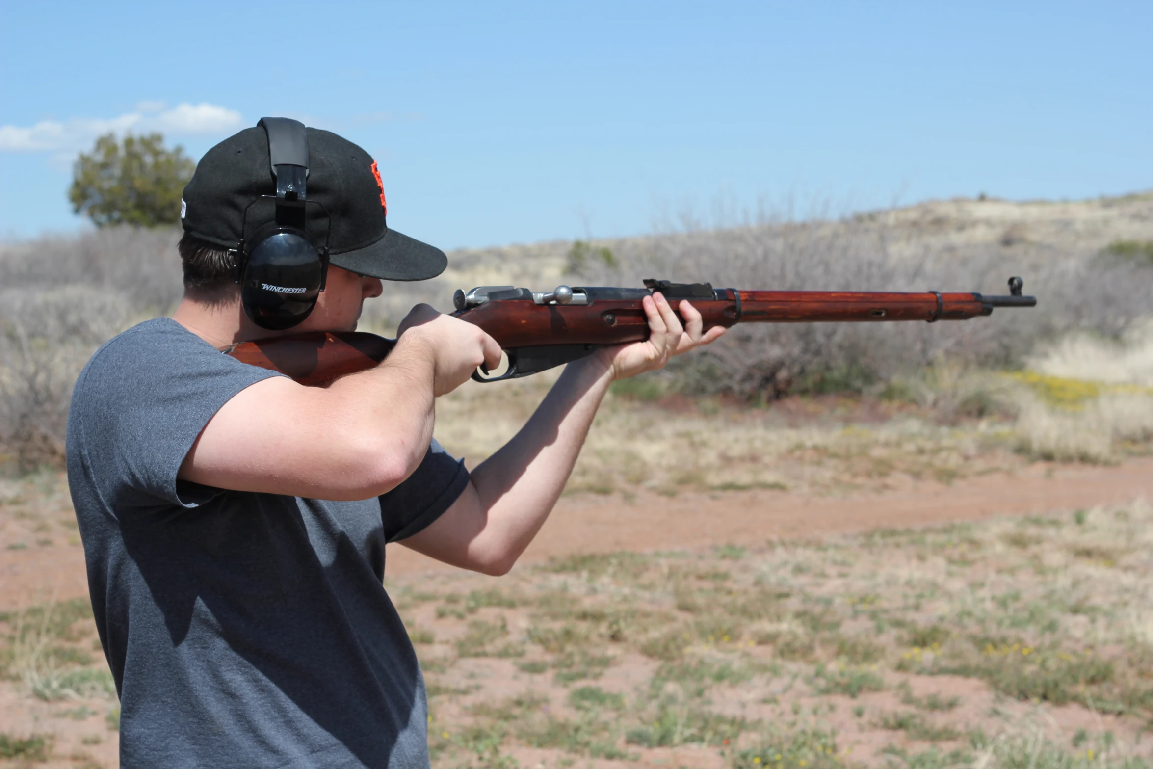 a man holding a rifle in his hands while wearing a hat