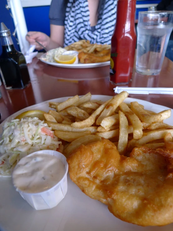 a plate filled with fish and fries next to a bowl of sauce