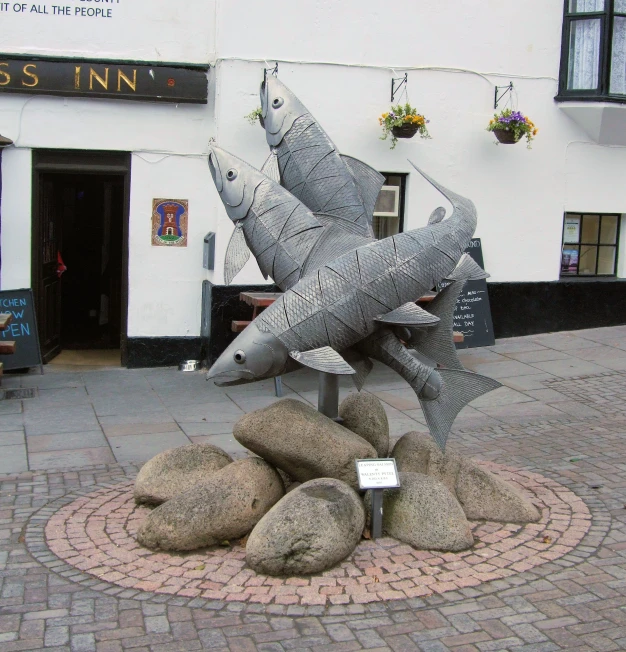 two big fake sharks are standing on top of large rocks