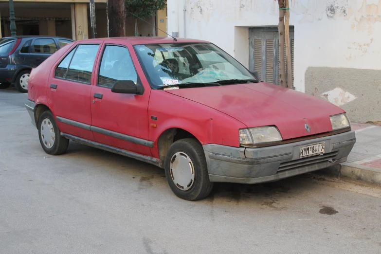 a red car parked on a city street next to a building