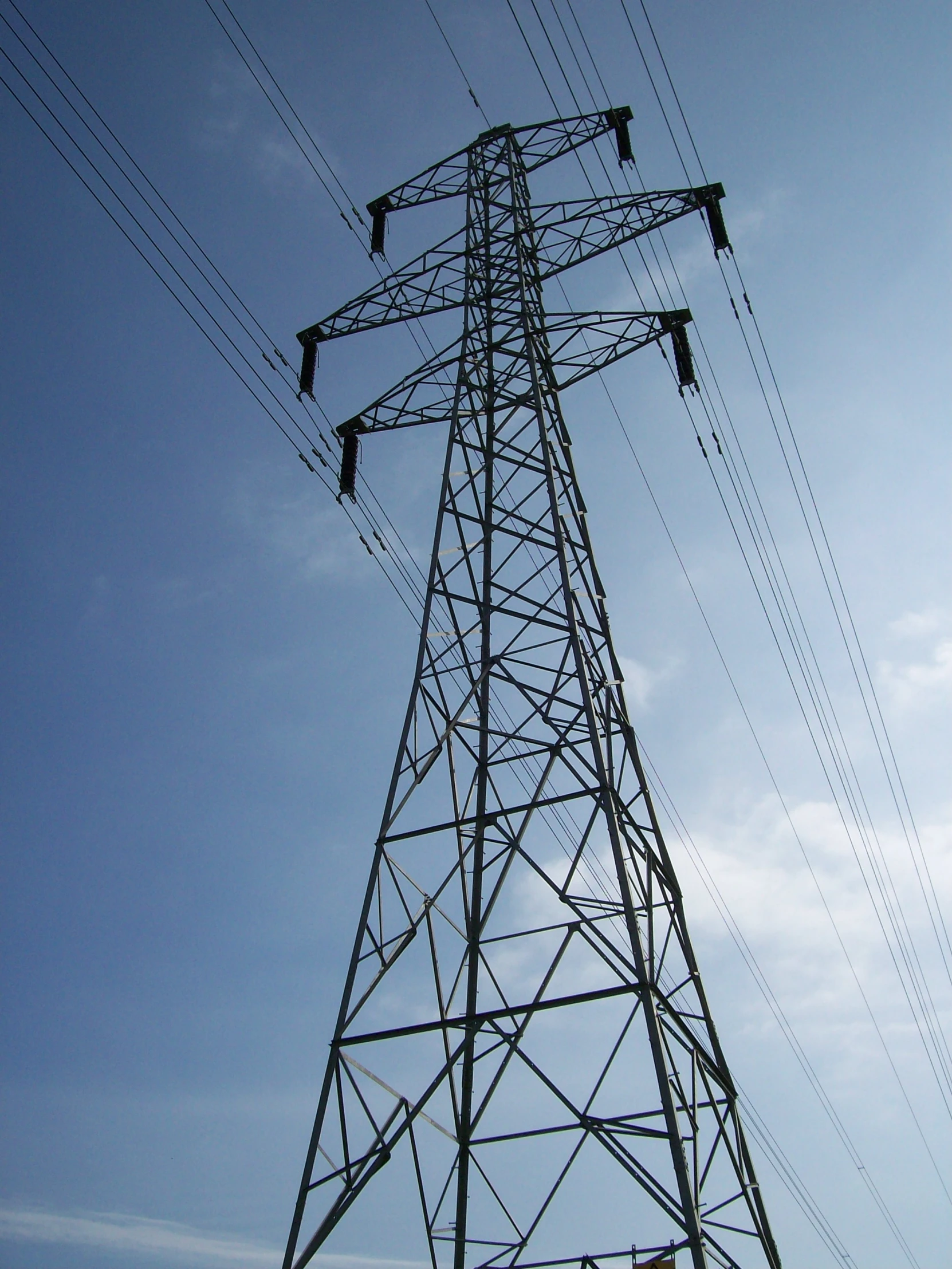 the top of a power tower with some birds flying over it