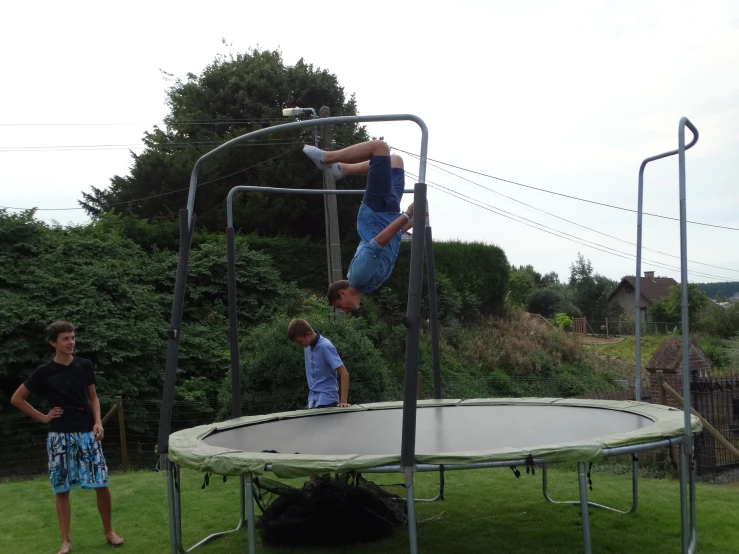 a boy and his friend playing on a trampoline in the grass